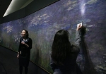 Nicole Myers, Associate Curator of European Painting and Sculpture at the Nelson-Atkins Museum of Art, left, talks about Claude Monet&#039;s painting technique used on his painting &quot;Water Lilies&quot; as Mary Schafer, associate conservator, shines a light on a section of the work during a media preview, Friday, April 1, 2011, in Kansas City, Mo. For the first time in 30 years, the three panel work of the Impressionist artist will be on display at the museum and will run from April 9 through Aug. 7, 2011.