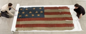 Workers preparing naval flags from the collection of H. Richard Dietrich Jr. for auction.