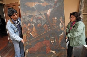Workers from the Culture Ministry display a recovered 18th century painting by an anonymous artist depicting Jesus in La Paz, Bolivia.