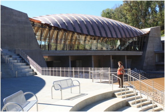 Courtyard and one of two copper-roofed structures that spans the ponds at Crystal Bridges, a new museum of American art opening in Bentonville, AR. The transparent structure, one of eight pavilions, hosts a restaurant.