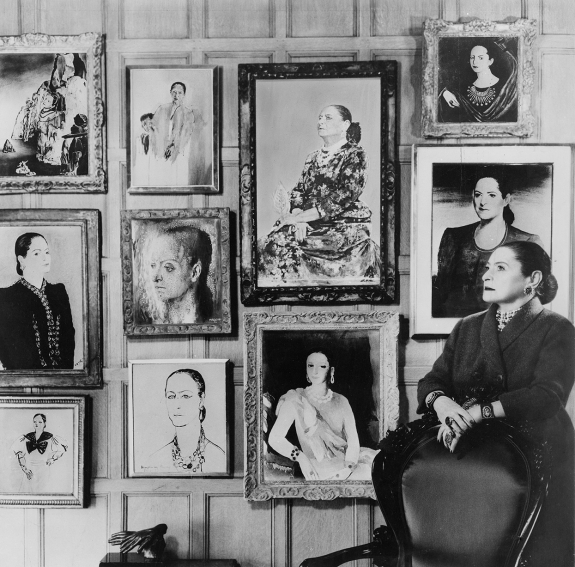 Helena Rubinstein in front of a montage of some of the many portraits she commissioned.