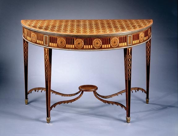 A rare and extraordinary pair of George III marquetry tables attributed to John Linnell, each with crossbanded marquetry tops centred with flowerheads, each frieze with gilt metal borders and trompe l’oeil flutes and paterai, on square tapered legs with entwined marquetry headed by husks, on ormolu stopped spade feet. Circa 1780, H. 33½, D. 20½, W. 51½ inches. Courtesy  of Clinton Howell Antiques.