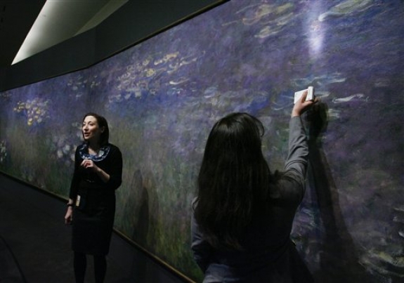 Nicole Myers, Associate Curator of European Painting and Sculpture at the Nelson-Atkins Museum of Art, left, talks about Claude Monet's painting technique used on his painting "Water Lilies" as Mary Schafer, associate conservator, shines a light on a section of the work during a media preview, Friday, April 1, 2011, in Kansas City, Mo. For the first time in 30 years, the three panel work of the Impressionist artist will be on display at the museum and will run from April 9 through Aug. 7, 2011.