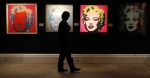 ﻿A Sotheby&#039;s employee poses in front of four screenprints all entitled &#039;&#039;Marilyn Monroe&#039;&#039; by Andy Warhol at Sotheby&#039;s in London September 13, 2010.