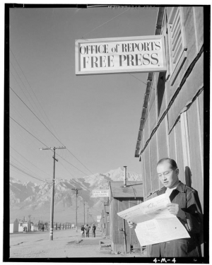 Internment camp: Roy Takeno reads a newspaper in front of the paper&#039;s office at the Manzanar Relocation Center in California. It is one of several scenes photographed in 1943 by Ansel Adams.