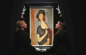Staff pose with &#039;Jeanne Hebuterne (au chapeau)&#039; from 1919 by Amedeo Modigliani at Christie&#039;s auction house in London. 